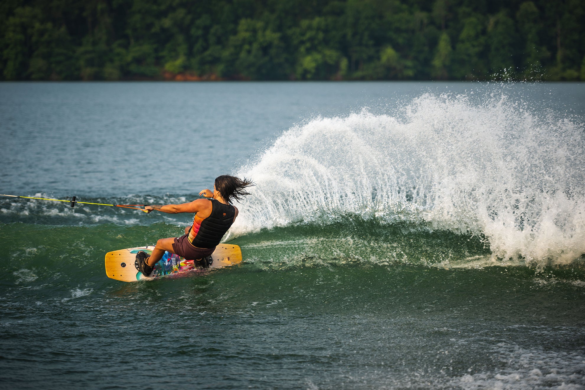 Person wakeboarding on a lake, creating a large spray of water.